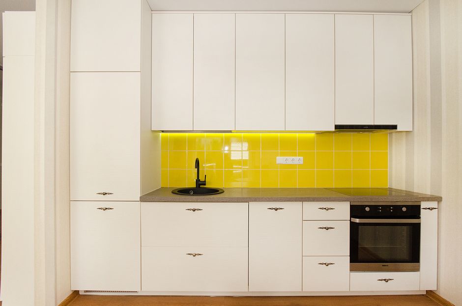 Stylish modern kitchen with white cabinets and a vibrant yellow tile backsplash.